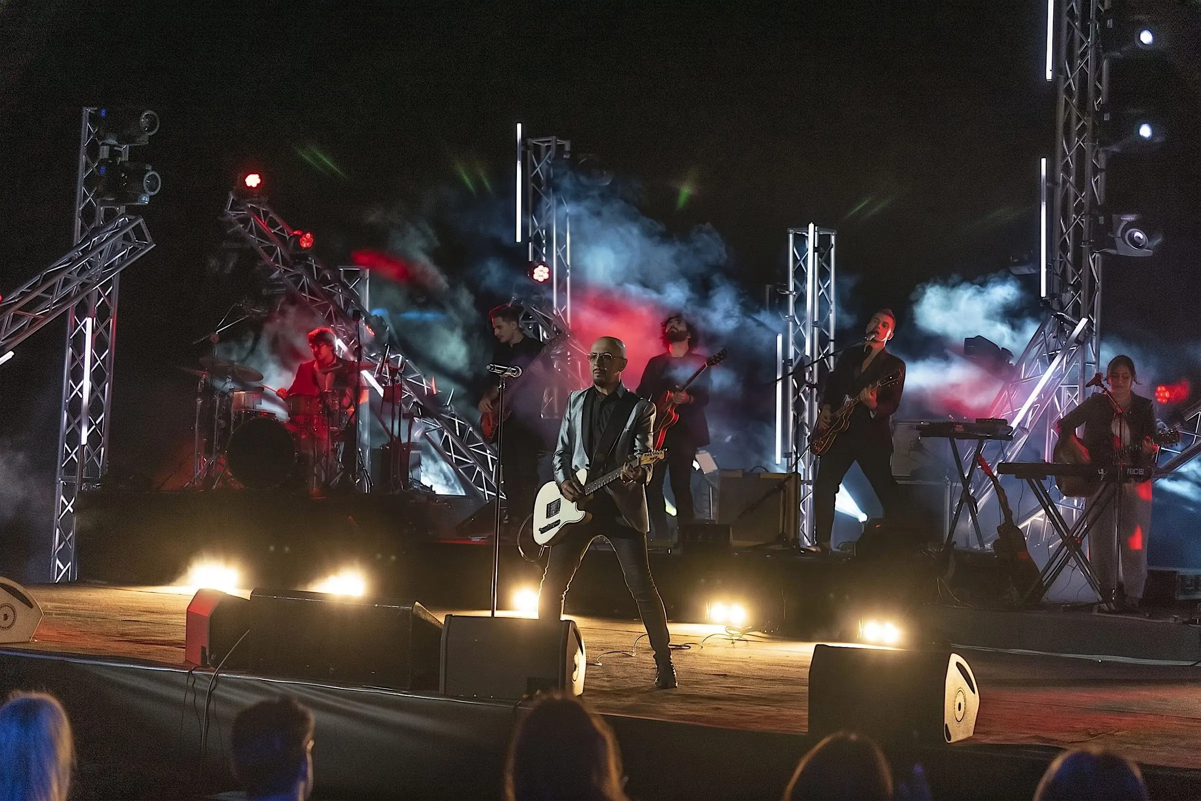 Band in concerto su un palco con americane, fumo e luci