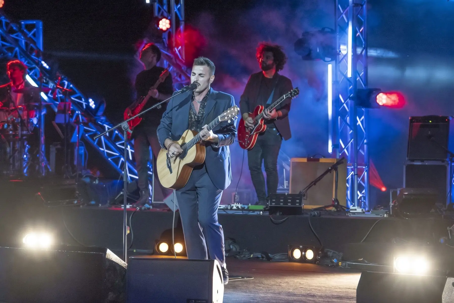 Cantante con chitarra su un palco con americane