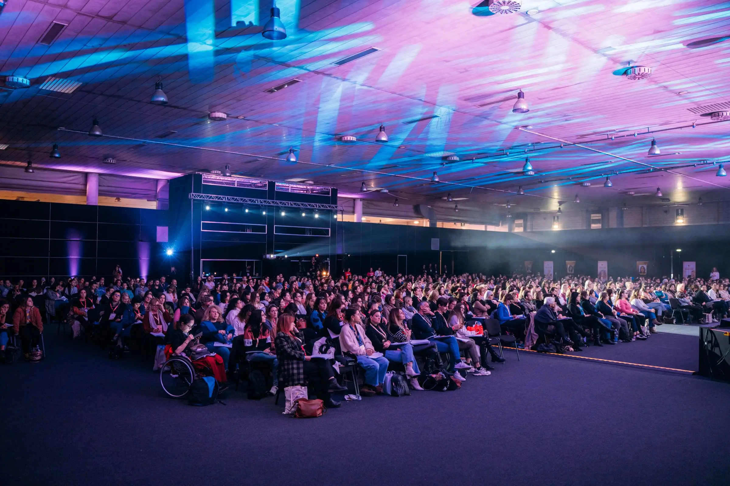 Platea gremita sotto fasci di luce viola e blu