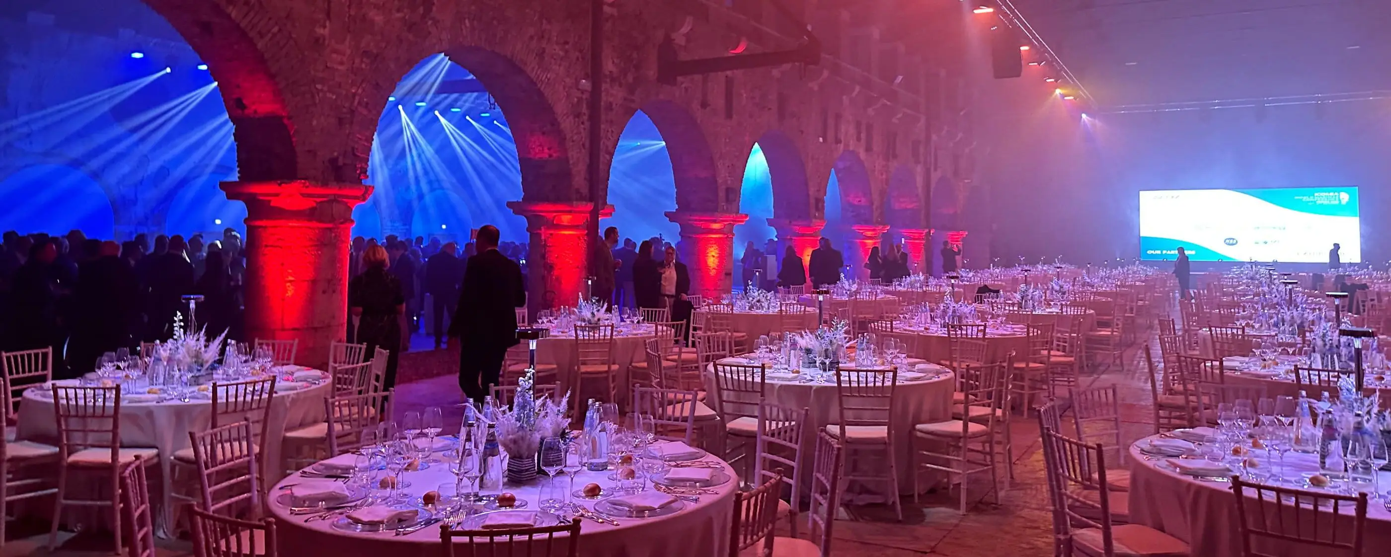 Cena di gala sotto arcate storiche con fasci di luce